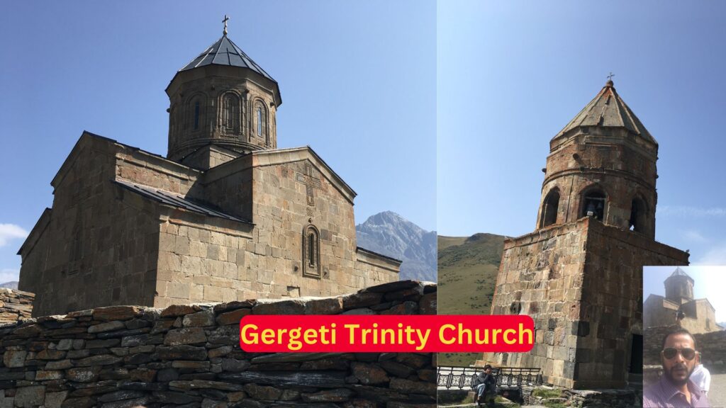 Man taking a picture in front of Gergeti Trinity Church with Mount Kazbek in the background.