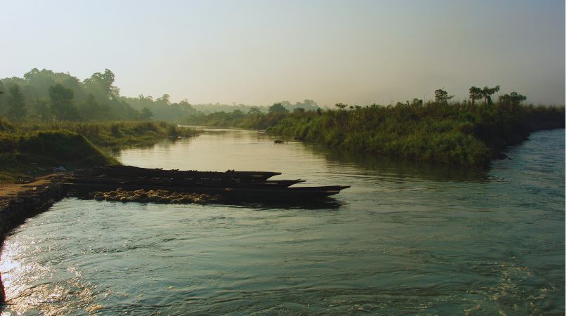 Tourists enjoying a peaceful canoe ride on the Rapti River in Nepal.