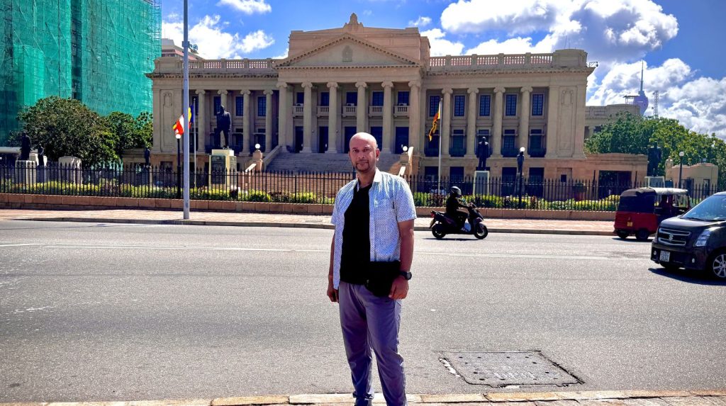 Person standing in front of the Old Parliament Building in Colombo with grand colonial architecture.