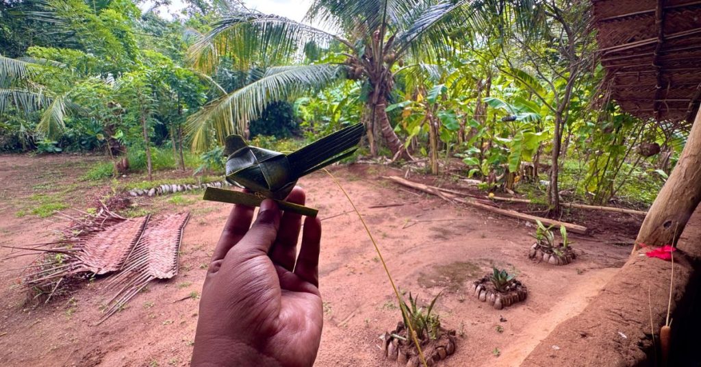 Tourist holding a handcrafted bird made of palm leaves inside a Hiriwadunna Village home in Sri Lanka.