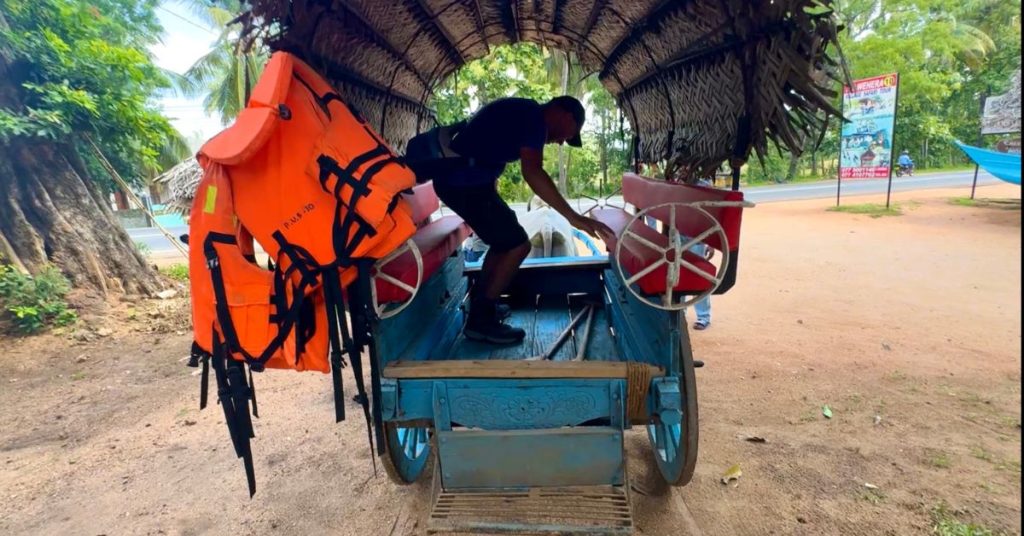 Person climbing onto a traditional bullock cart during Hiriwadunna village tour in rural Sri Lanka.